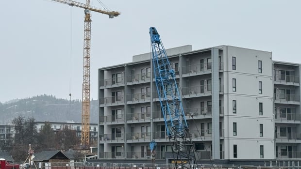 A photo of a five-storey apartment building on an overcast day with a construction site in the foreground.