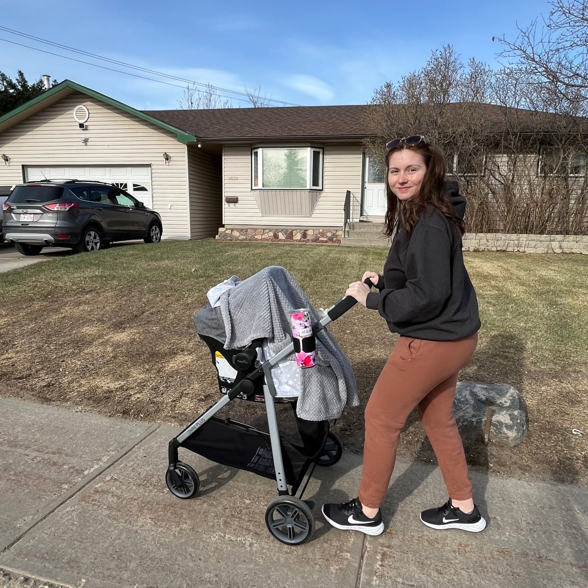 A woman pushing a stroller in a residential area.