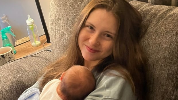 A woman smiles while holding a baby in her arms. 