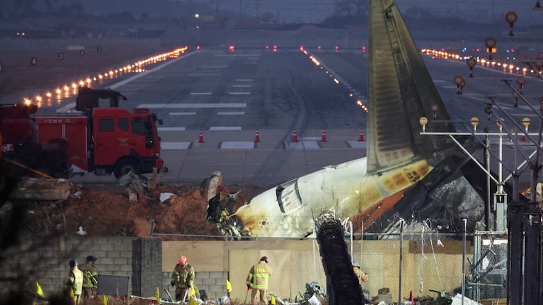 Rescuers work near the wreckage of a plane at night.