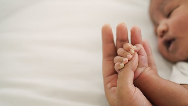 african american new born baby hand holding mom finger on white bed. Asset ID: 1819247924 african american new born baby hand holding mom finger on white bed.