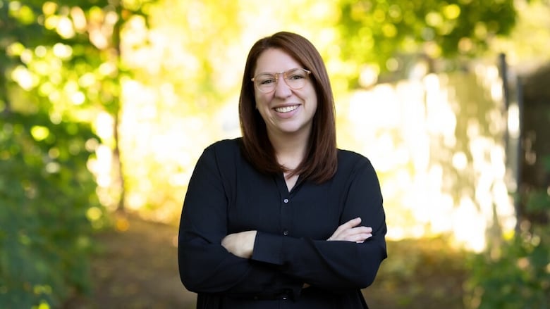 A woman smiling into the camera with her arms crossed.