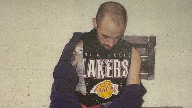 This photo of Zakkary Reed was part of a Crown exhibit entered into evidence on Monday, the first day of Reed's trial. Man sits with his head down, one hand bloody and the other wrapped in a plastic bag.