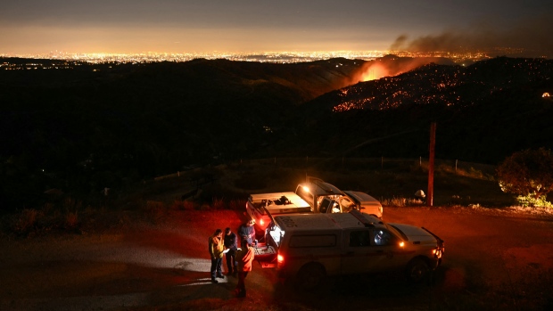Death toll rises to 24 in California wildfires as crews brace for incoming severe weather; TOPSHOT - The downtown Los Angeles skyline \(far L\) is seen in the distance as firefighters monitor the Palisades fire near the Mandeville Canyon neighborhood and Encino, California, on January 11, 2025\. The Palisades Fire, the largest of the Los Angeles fires, spread toward previously untouched neighborhoods January 11, forcing new evacuations and dimming hopes that the disaster was coming under control\. Across the city, at least 16 people have died as multiple fires have ripped through residential areas since January 7, razing thousands of homes in destruction that US President Joe Biden likened to a "war scene\." \(Photo by Patrick T\. Fallon / AFP\) \(Photo by PATRICK T\. FALLON/AFP via Getty Images\)
