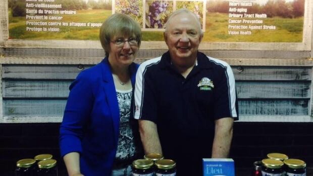Diane and Murray Tweedie operate Wild Blueberry Meadows Farm in Kouchibouguac. middle-aged man and woman standing in front of table piled with blueberry products