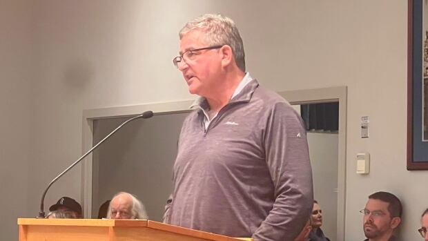 Colter told the committee that the initial design had become too expensive due to the inset balconies. A man speaks at a podium