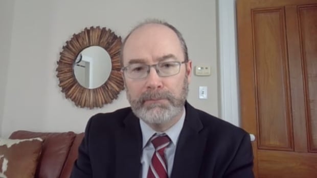 Matt MacFarlane wears a suit while looking into the camera on a Zoom call.