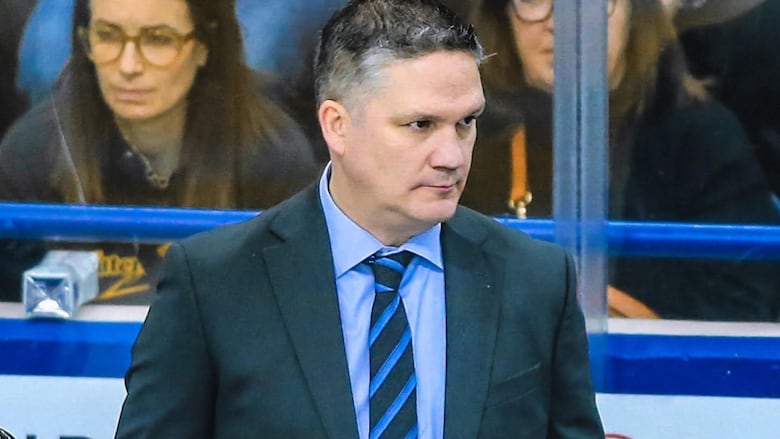 A man in a suit looks off camera.