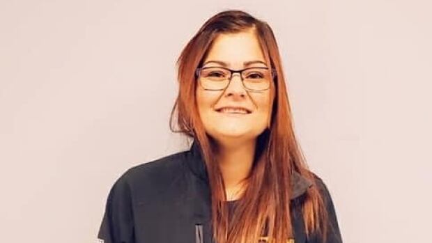 A woman with glasses and long hair smiles for a posed photo.