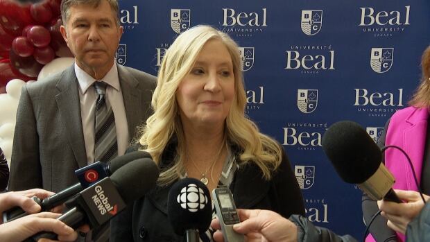 Sheryl DeWalt, president of Beal University, said several years ago, Opportunities New Brunswick contacted Beal and asked if the university would consider opening a Canadian campus. A woman with long blond hair speaking into a cluster of microphones.