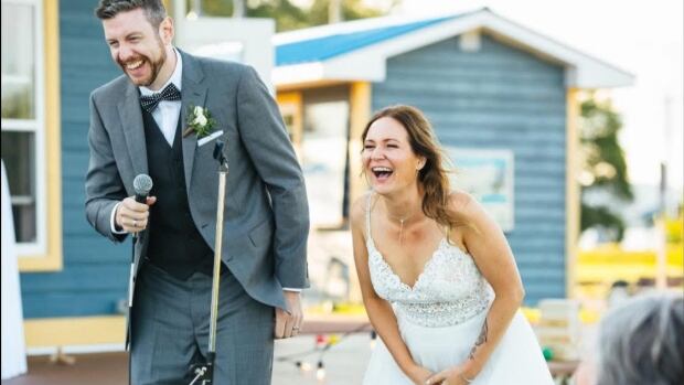 John and Cathy Foote were married in 2021 and bought their first house in Saint John a year later. In 2024 they were billed $649 more in property tax than the average charged to ten other houses in the city with identical assessments. A young man in a blue suit and a woman in a wedding gown dance are laughing outside in front of a microphone.