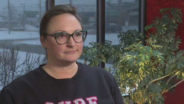 Ashley Clark wears a black crew neck and glasses.