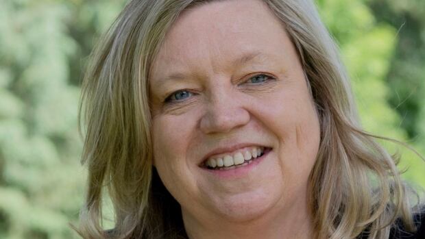 Jeannie Hunter is one of the nominees for MusiCounts Teacher of the Year. Jeannie has blue eyes and blonde hair and she smiles while sitting outside against an out of focus green backdrop.