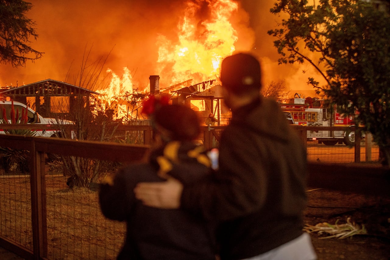 two people looking at a burning house