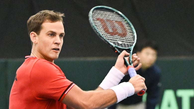 A men's tennis player hits a return shot.