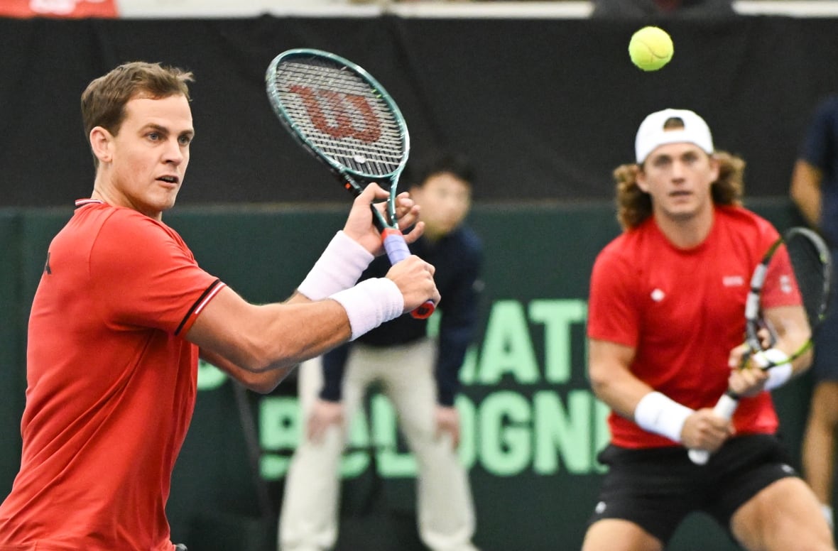 A men's tennis player hits a return shot.