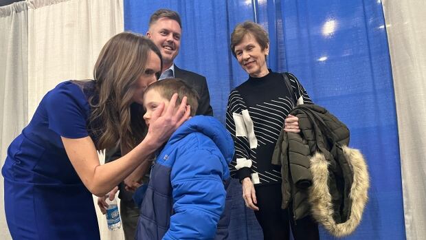 Natalie Jameson, left, kisses her son, Henry, on the head as her husband, Dennis, and her mom, Christa Curran look on at a nominating convention at the Eastlink Centre on Thursday. Jameson is seeking the Conservative nomination in the federal riding of Charlottetown. A woman in a blue dress kisses her son on the head and two other people look on.