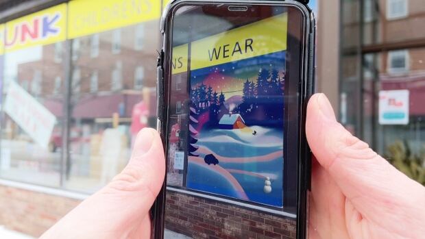 As part of the city's Winter Warmth Festival, Explore Summerside commissioned Island artists to create original murals that incorporate augmented reality and are displayed in storefronts along Water Street. Hands holding a smartphone taking a photo of a mural.
