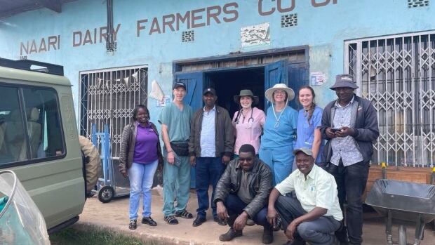 A group of nine people outside a building labeled "Naari Dairy Farmers Co-op"