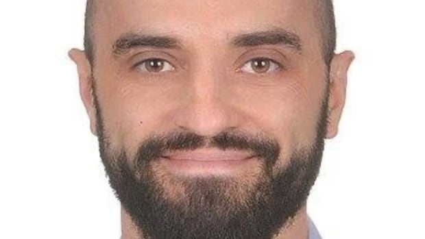 Roman Kamyshnyy, 45, remains in hospital. A smiling man with a beard, wearing a blue collared shirt.