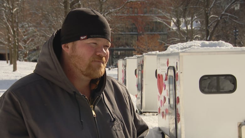 A man is interviewed by a reporter outside.