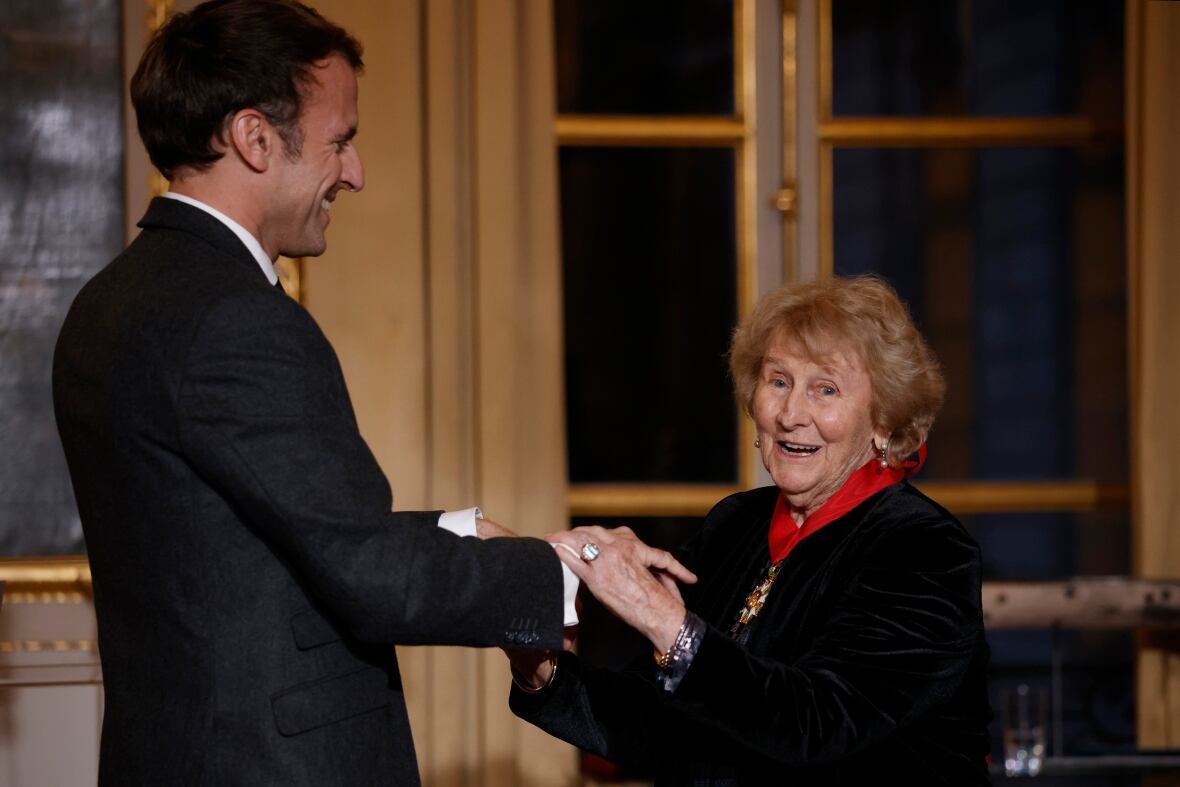 A smiling aged  pistillate   shakes a man's hand.