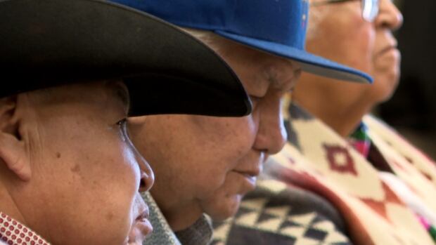 Elders attend a summit at Tsuut’ina Nation over the weekend. The gathering was held to develop a strategy to bring to the government in response to what elders say is a lack of consultation in the province's development of new K-12 curriculum. Several people, one in a cowboy hat, look somewhere out of the frame.