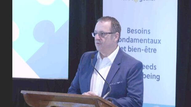 Stéphane Leclair, the CEO of the Economic and Social Inclusion Corporation, outlined the Crown corporation's 2025-30 poverty reduction plan in Campbellton on Wednesday. A man in a blue suit jacket standing at a podium.