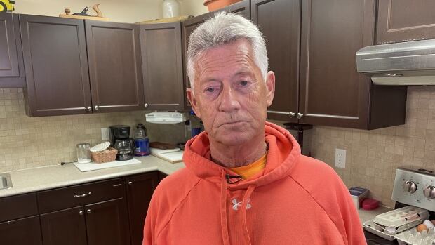Bobby Hayes is the representative plaintiff in a class-action lawsuit against the City of Saint John for harm caused by a former police officer who sexually assaulted children. The suit, filed in 2013, is now trying to sort out a process for determining individual damages. Grey-haired man in a red hoodie looks straight at the camera.