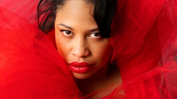 Dee Hernandez will perform at the Paddlefest Music and Nature Festival. A woman with dark hair, red lipstick and a red dress stares up into the camera.