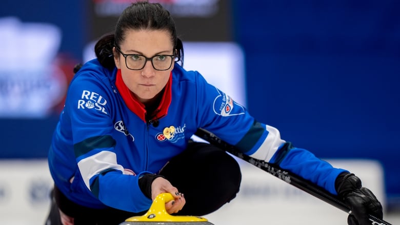 A female curler delivers a stone.
