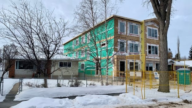 A three-storey, multi-family dwelling being built in the west end Grovenor neighbourhood in February 2024. Grovenor is one of the communities adjacent to the Valley Line West LRT, which is currently under construction. A three-building being built next to a single family bungalow.