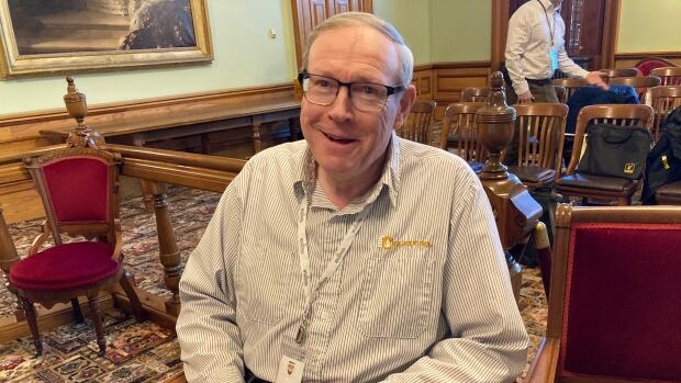 'We are held hostage because of this situation,' Peter Clark, the owner of Woodstock-based Clark Oil, told the legislature’s law amendments committee. A man smiling with his mouth open. He sits in a chair with his hands folded on his lap.