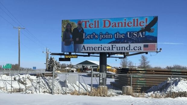 This billboard has been erected in Bowden, Alta., overlooking the highway that connects Edmonton to Alberta. Despite widespread backlash locally, the town's mayor says there's nothing he can do about it. A billboard overlooks a highway on a snowy day. It features a picture of U.S President Donald Trump and Alberta Premier Danielle Smith smiling as an eagle flies by in the background. In big letters, it reads: "Tell Danielle! Let's join the USA! AmericaFund.ca" An American flag is in the lower-right corner.