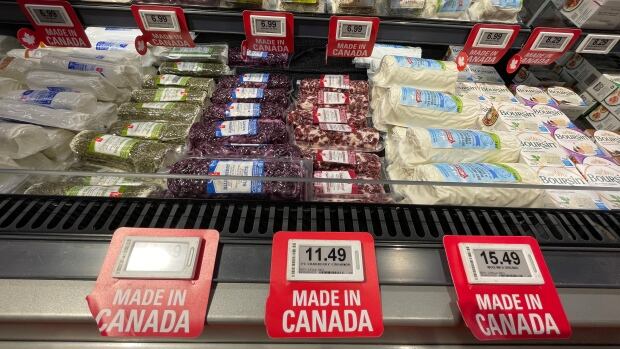 Grocery stores like this one in downtown Edmonton are marking products that are made in Canada, as potential U.S. tariffs loom on the local economy A row of cheese in a grocery case. The price tags have red signs around them that say made in Canada in all capital letters.