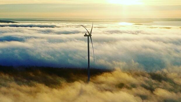 The Wisokolamson Energy Project, located in Albert County, was built in partnership with Woodstock First Nation and SWEB Development. Aerial view of a wind turbines surrounded by clouds