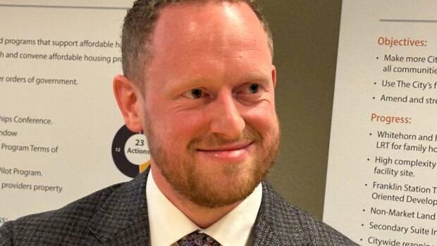 New chief housing officer vows to implement city’s housing strategy in the years ahead. A man in a suit smiles at the camera.