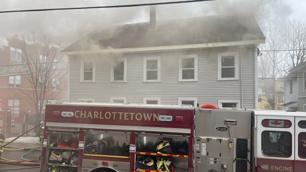 A Charlottetown firetruck is parked outside of a building that is surrounded by smoke.