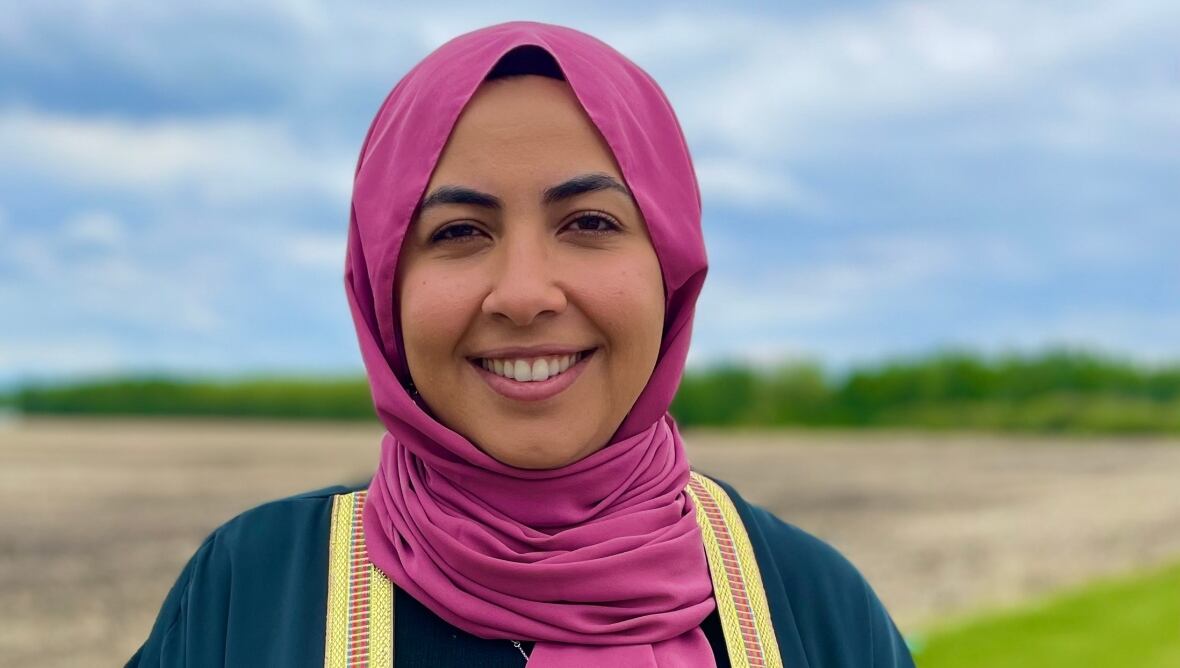 A woman wearing a hijab smiling at the camera. 