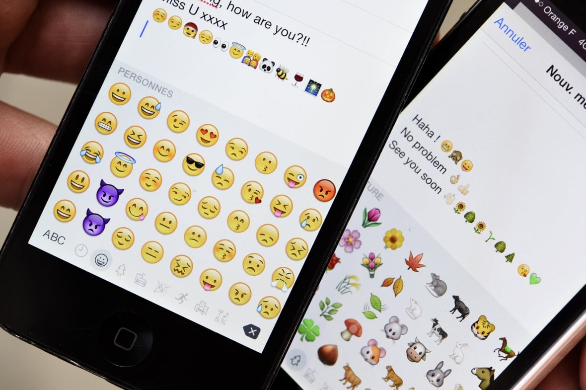 A picture shows emoji characters also known as emoticons on the screens of two mobile phones in Paris on August 6, 2015.
