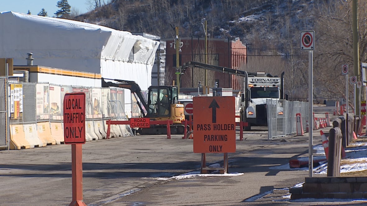 A road where lots of construction is taking place. There are two signs up that say "local traffic only" and "pass holder parking only."