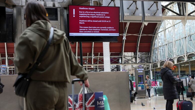 People basal   with their backs to the camera carrying and guiding luggage, portion    looking toward an physics  bulletin committee  that says Heathrow Airport is closed.