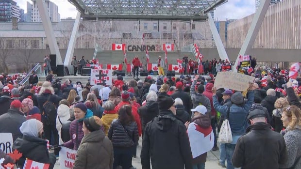 A large crowd gathered in downtown Toronto for an "Elbows Up" rally Saturday in response to tariffs and annexation threats coming from the U.S. government. A crowd of several thousand, many holding Canada flags stand in front of a stage at Nathan Phillips Square on a grey afternoon