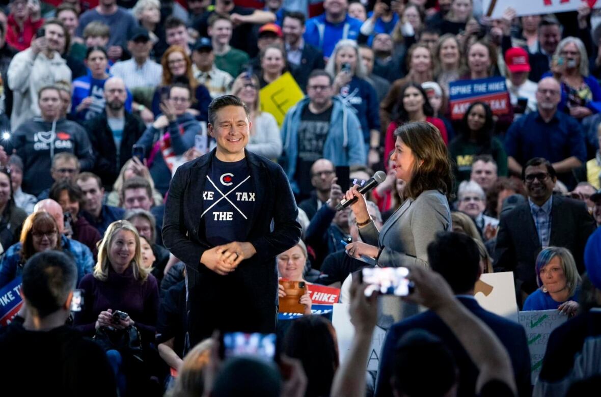 two politicians on a state surrounded by a rally crowd