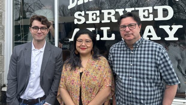 From left to right, Connor Kuznik, Sammie Jo Rumbaua and Tyronne L'Hirondelle discussed why Trump and the cost of living are dominating their ballot decisions in the federal election. two men with glasses, one older and one younger, stand on either side of a woman. they're in front of the window of a breakfast restaurant