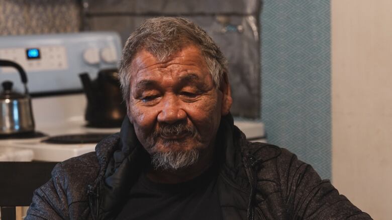 Head-and-shoulders representation    of a middle-aged First Nations antheral   with a mustache and grey goatee.