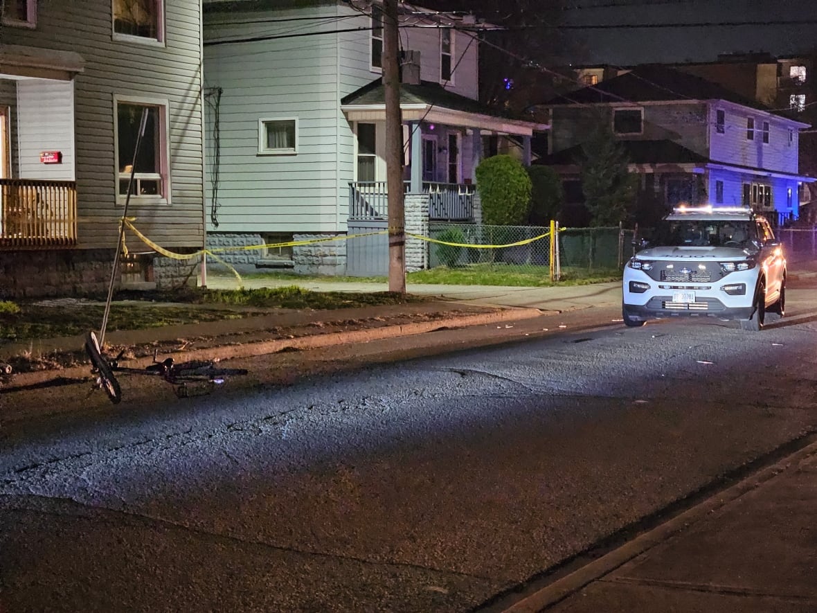 A bicycle lays on a road with a police cruiser behind it. 