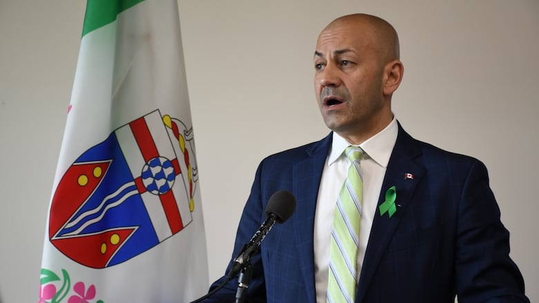 A man standing behind a podium with a Yukon flag next to him. 