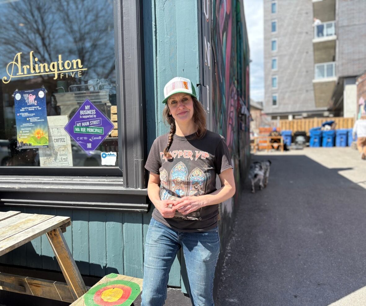 Woman stands in front of coffee shop.