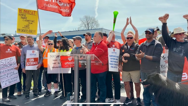 A group of workers with strike signs raise their hands and fists.